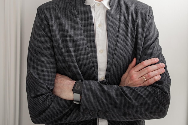 A man in a white shirt and jacket near a brick wall