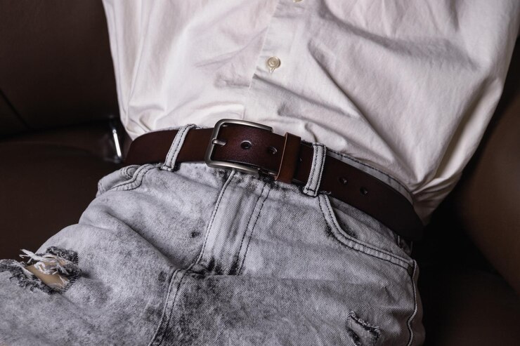 Photo man in white shirt and light jeans with brown leather belt
