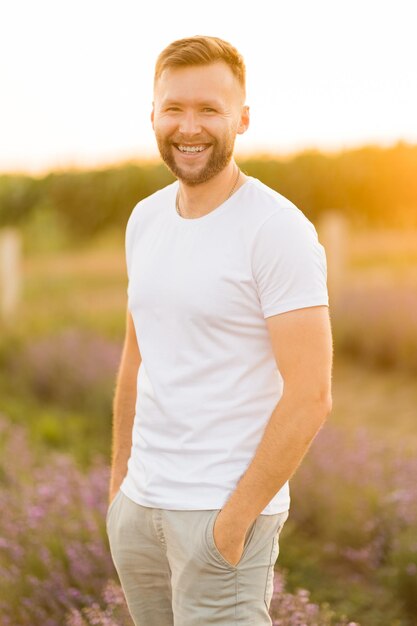 Мужчина в белой рубашке стоит на лавандовом поле.