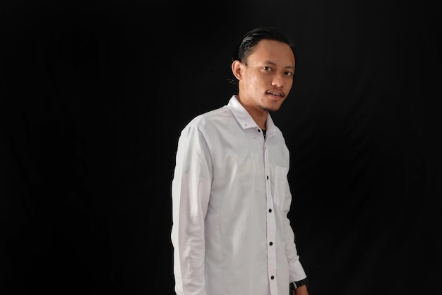 A man in a white shirt stands in front of a black background.