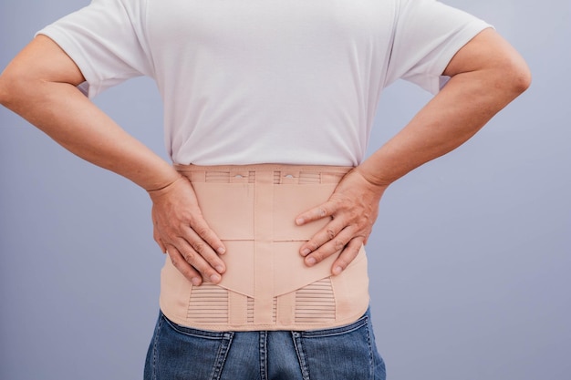 Un uomo con una camicia bianca indossa una cintura per alleviare il dolore alla schiena