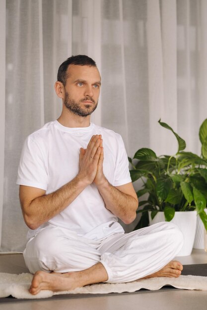 A man in white sportswear is doing yoga with a fitness room the concept of a healthy lifestyle
