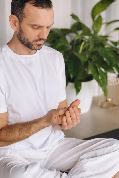 A man in white sportswear is doing yoga with a fitness room the concept of a healthy lifestyle