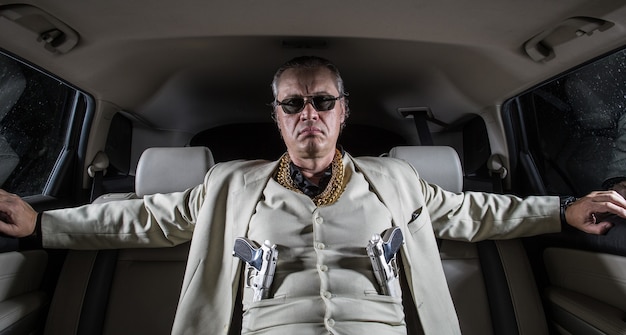 Foto uomo in abito bianco con una mafia del gangster di pistola in macchina