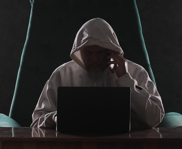 man in white sweatshirt sitting with laptop