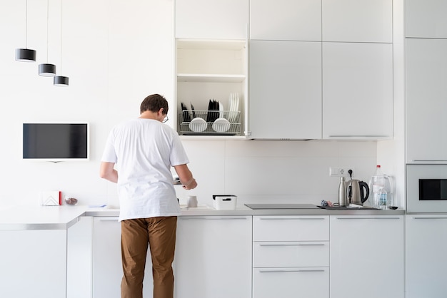 Photo man in white t shirt washing dishes in the kitchen