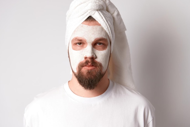 Man in white tshirt apply facial mask stand against white background Self care morning spa procedure