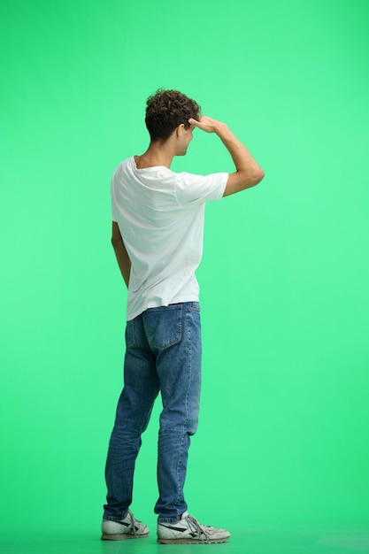 A man in a white Tshirt on a green background in full height