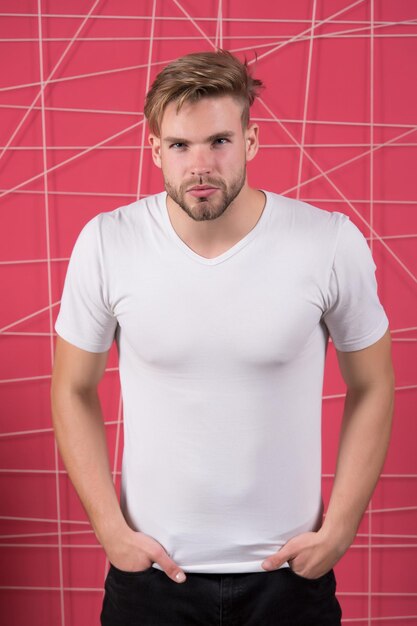 Man in the white tshirt with copy space standing on pink wall background.