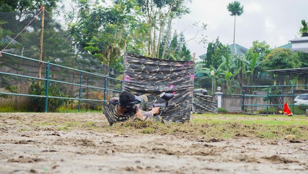 A man who was hit by a bullet and fell down crossfire with\
enemies in paint ball game