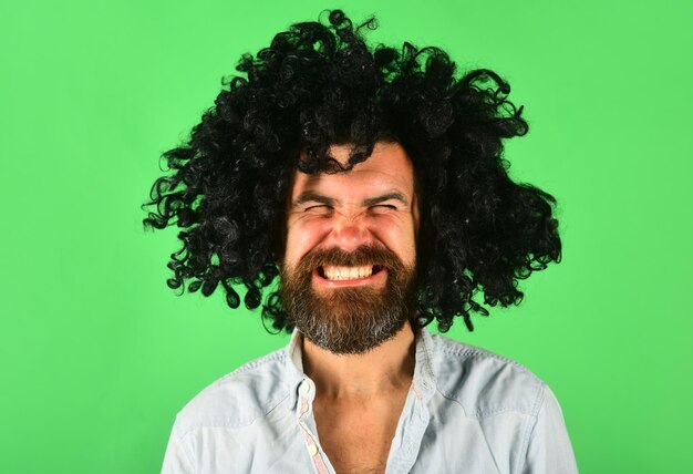 Мужчина в парике. Улыбающийся человек в кудрявом парике. Счастливый человек в парике цвета. Улыбка. Крупным планом портрет улыбающегося бородатого мужчины. Изолированный.
