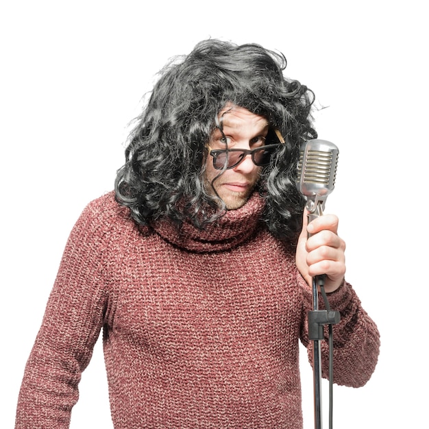 Мужчина в парике, свитере и солнцезащитных очках держит изолированный микрофон