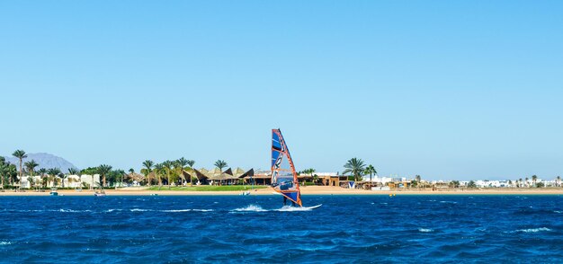 晴れた空の下で海でウィンドサーフィンをしている男性