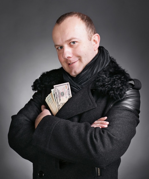 man in winter coat with money isolated on grey