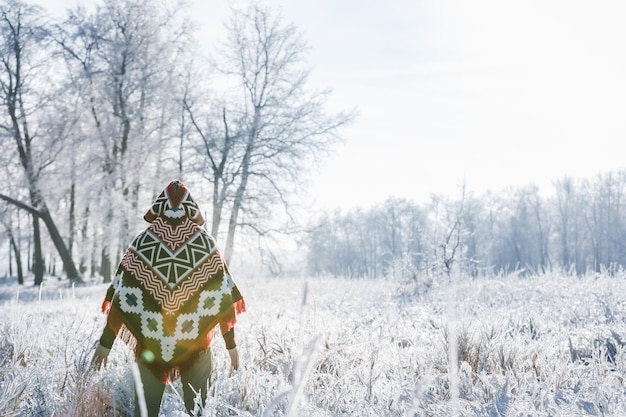 A man in a winter forest alone in a poncho a walk in nature