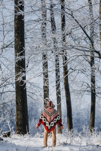 A man in a winter forest alone in a poncho a walk in nature