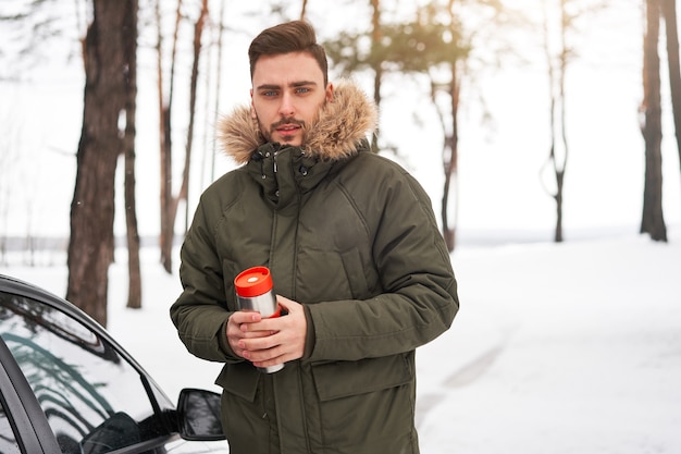 Man in winter forest near car