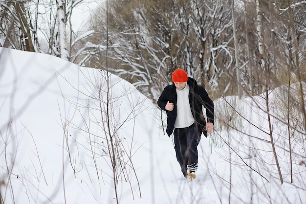 A man in the winter in the forest. A tourist with a backpack goes through the woods in winter. Winter ascent.