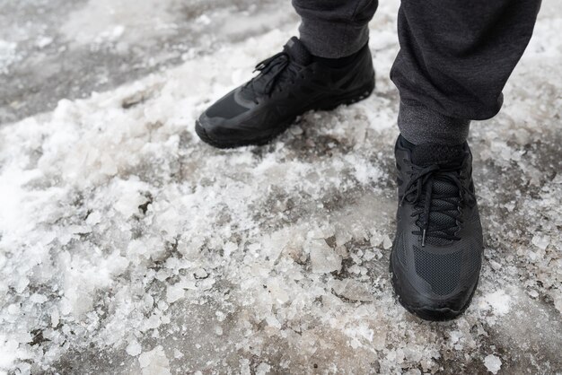 A man in winter waterproof sneakers stands on an icy road shoes for winter walks walks in the open air