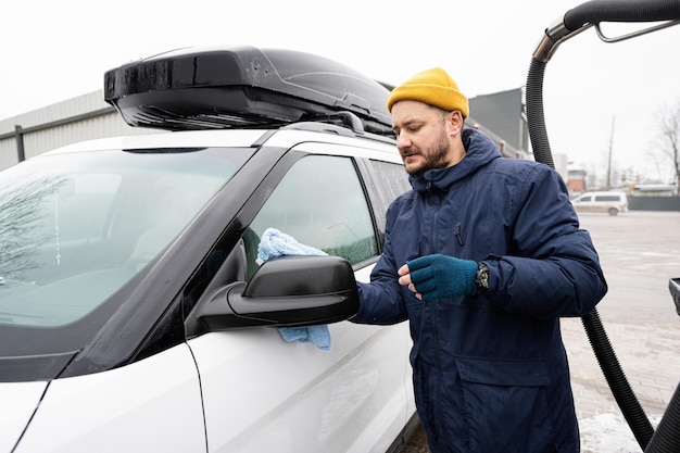 寒い季節にアメリカのSUV車のミラーを洗った後、男性がマイクロファイバーの布で拭く