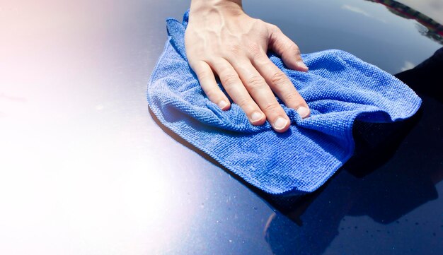 A man wipes a car with a microfiber cloth Car polishing