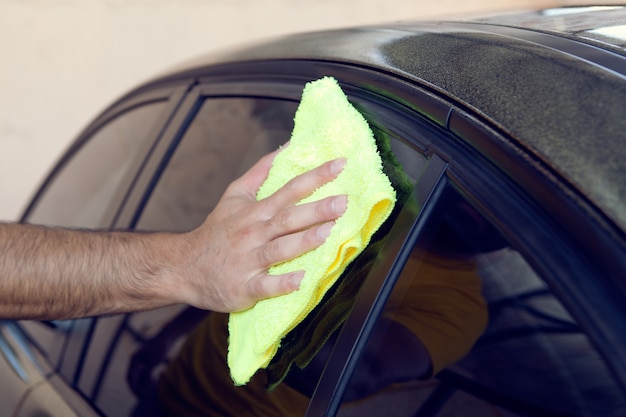 A man wipes a car with a rag