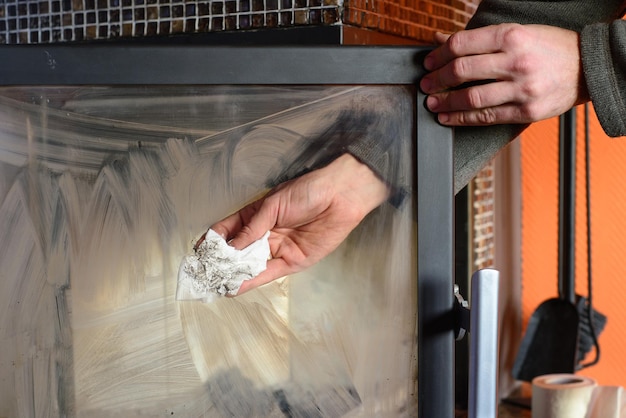 Man wipes the dirty glass of fireplace