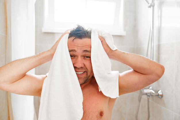 Photo a man wipes himself with a towel after a shower textiles for the bathroom
