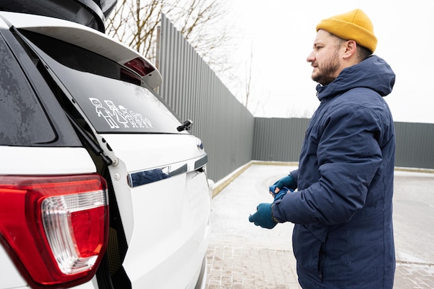 Man wipes trunk of american SUV car with a microfiber cloth after washing in cold weather