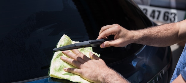 Photo a man wipes a wet car with a rag