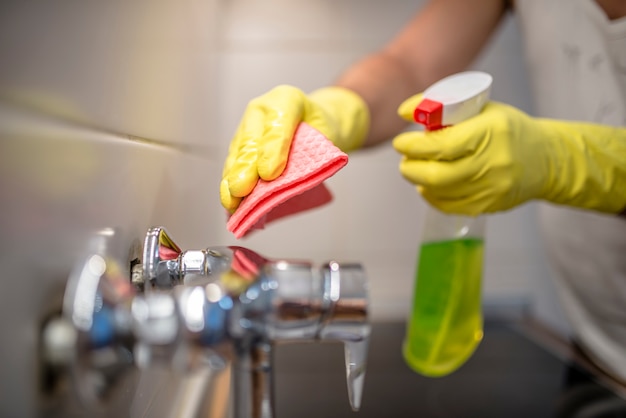 Photo man wiping faucet in kitchen.