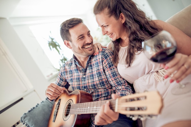 Man with acoustic guitar singing for smiling woman