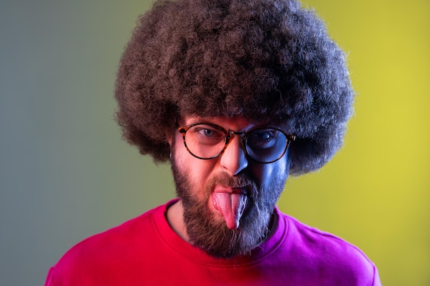 Man with Afro hairstyle showing out tongue with naughty disobedient grimace making face