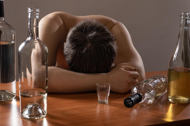 A man with an alcohol addiction sleeps at a table