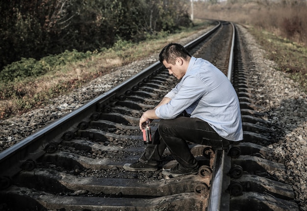 야외에서 철도 트랙에 알코올을 가진 남자입니다. 여행 개념입니다. 외로운 사람. 자살 개념입니다. 우울증.