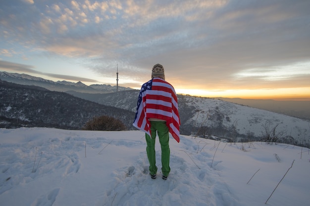 man with american flag in the mountains in winter