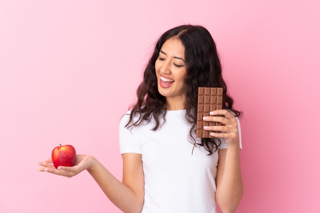 Man with apple in one hand and chocolate in the other