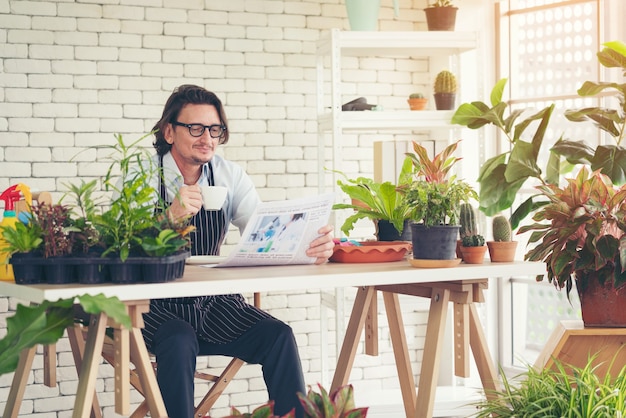 man with apron in greenhouse drinking coffee