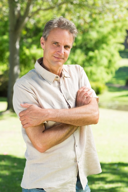 Man with arms crossed in park