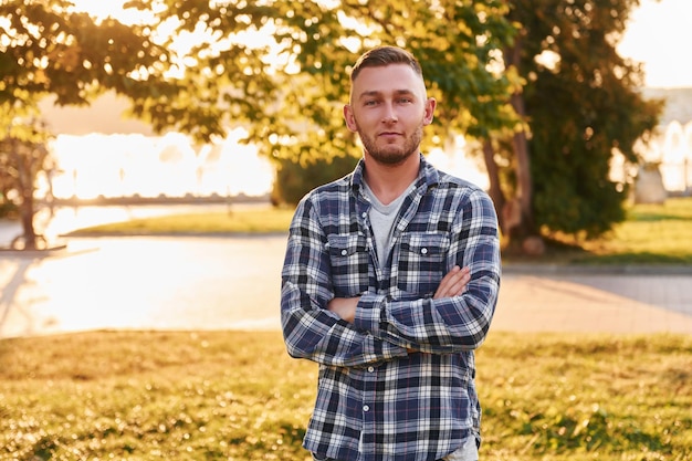 Photo man with arms crossed standing in the park at daytime