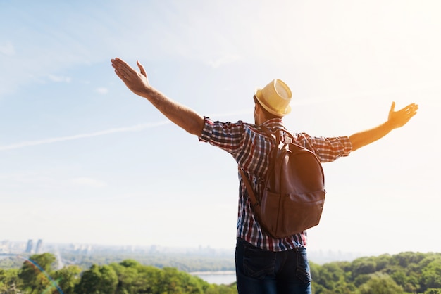 Man with arms outstretched against beautiful green landscape