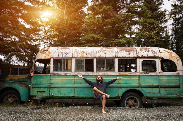 Photo man with arms outstretched sitting against abandoned bus