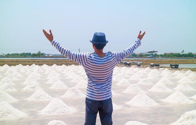 Man with arms outstretched to the sprawling salt pan in the harvest season Thailand