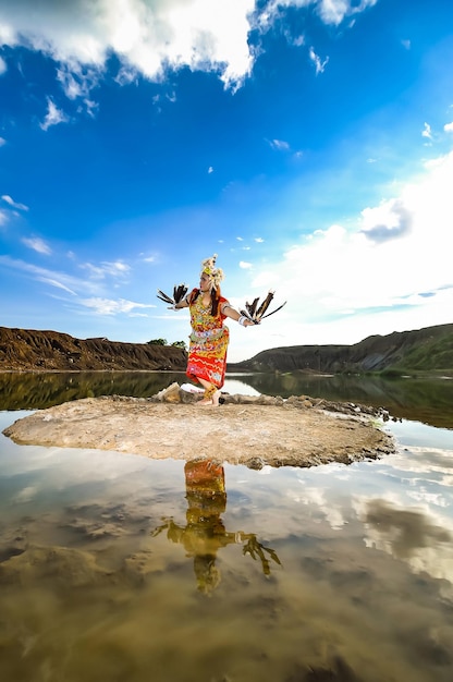 Man with arms outstretched in water against sky