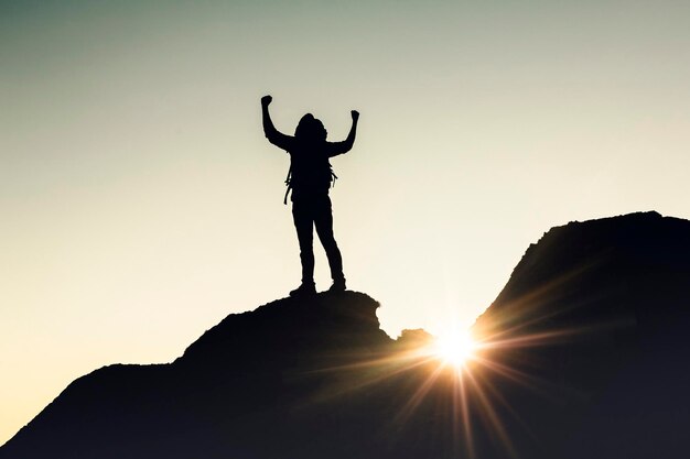 Man with arms raised at sunset