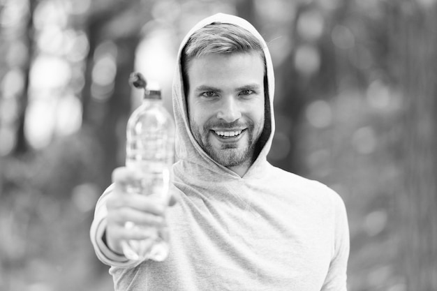 운동 외모를 가진 남자는 물이 든 병을 보유하고 있습니다. 스포츠 의류 훈련 야외 스포츠 및 건강한 라이프 스타일 개념 운동 선수는 훈련 후 물을 마신다.
