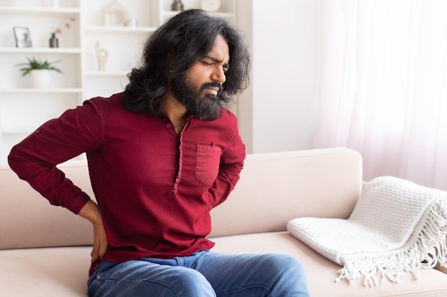 Man with back pain on a modern sofa