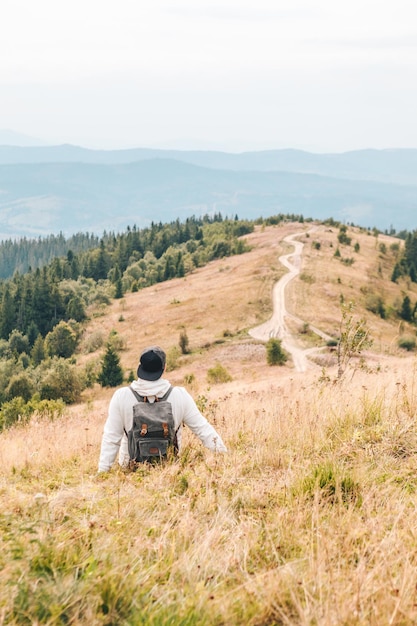 Man with backpack hiking by autumn mountains