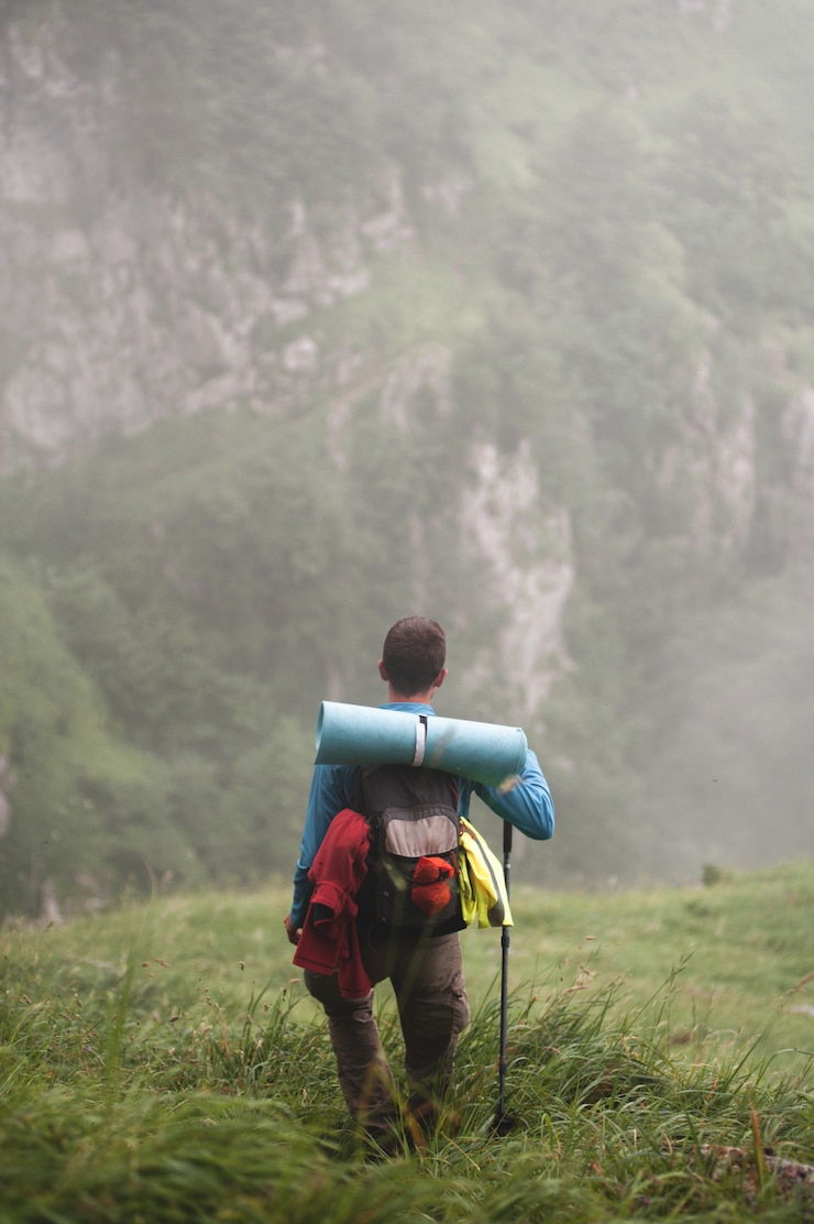Photo man with backpack hiking down the mountain