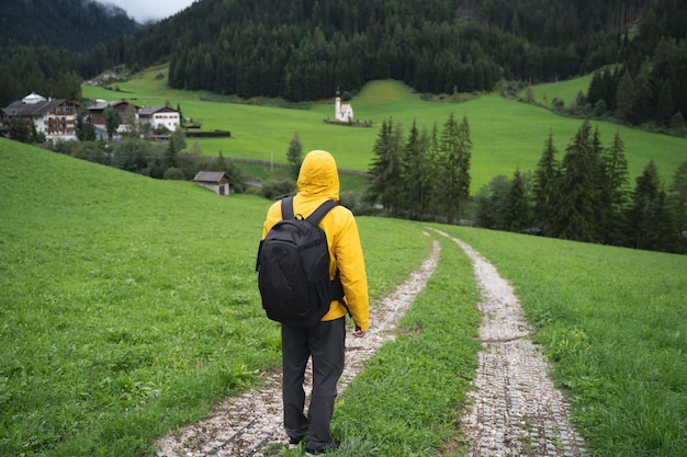 A Man with backpack on hiking trail to St Johann church in Val di Funes valley Dolomites Italy Europ